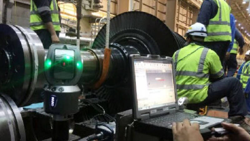 Workers around a large machine referencing FARO 3D scanning data on a laptop 