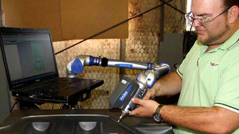 A worker at Trinity Forge using a FARO ScanArm to inspect a large die