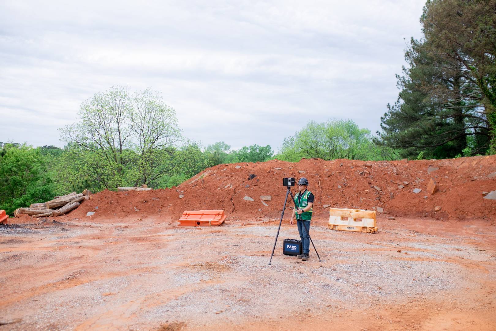 Man in PPC scanning a large open outdoor space with a terrestrial laser scanner