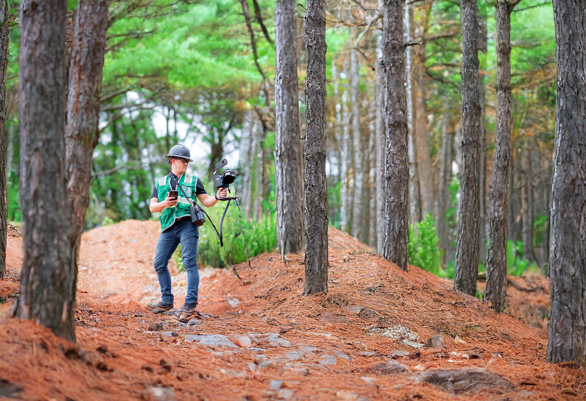 A man mobile mapping a forest in personal protective clothing, using a FARO Orbis Premium