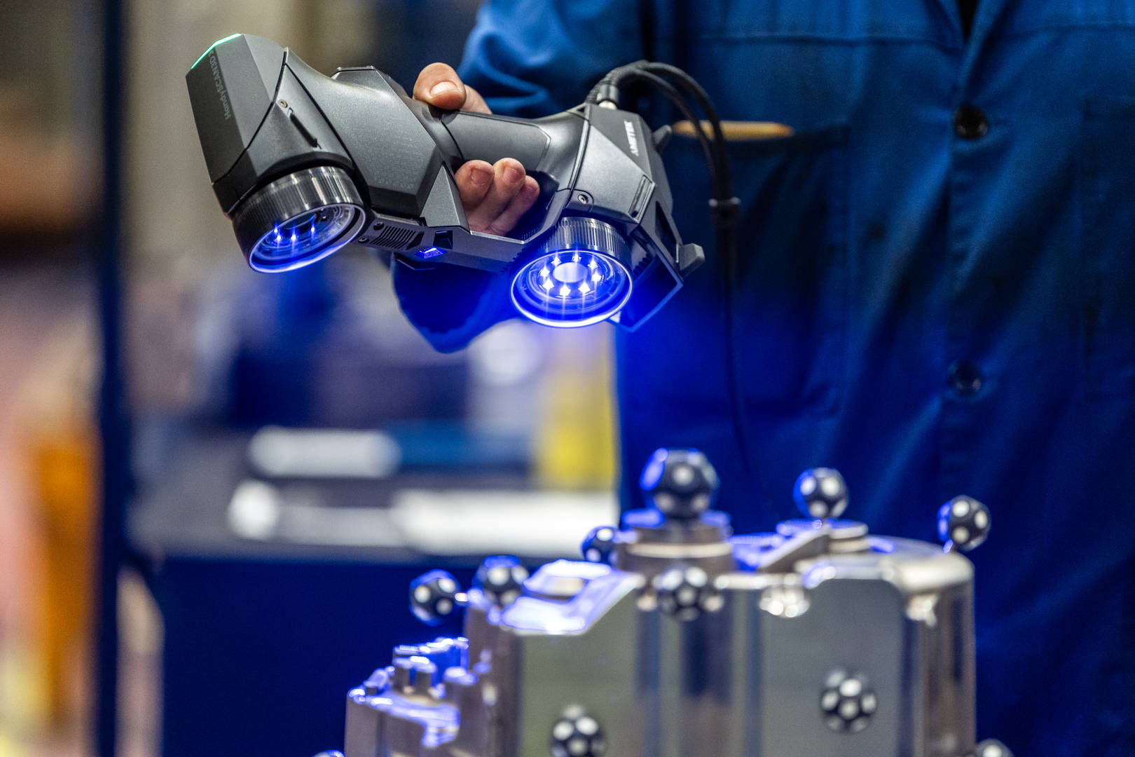 Handheld 3D scanner measuring an industrial casting component for quality inspection.