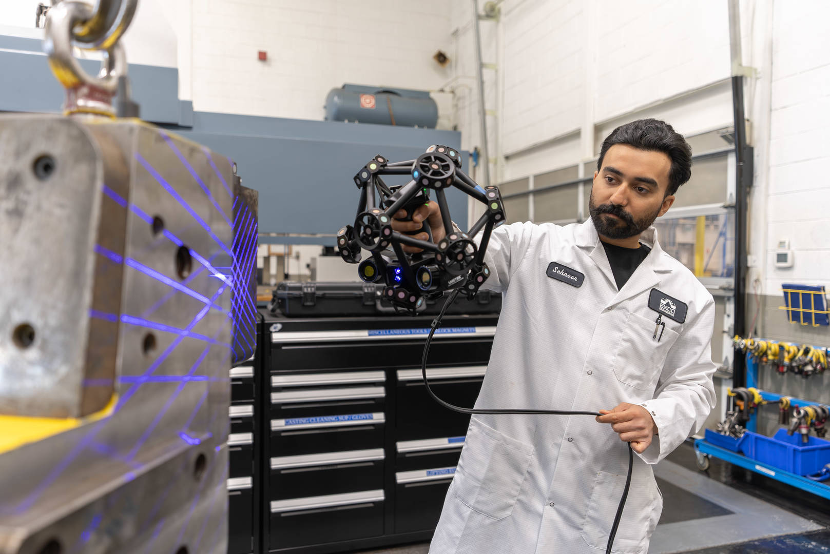 Technician performing 3D inspection with a handheld scanner in a manufacturing environment.
