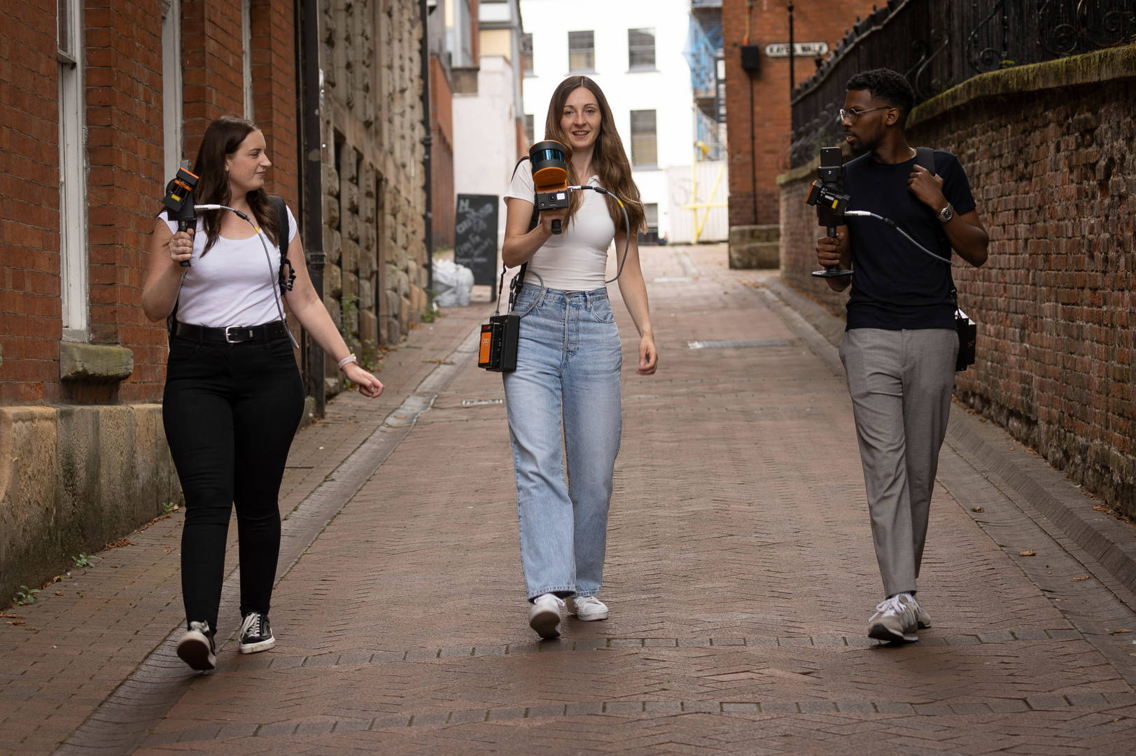 3 people walking down the street with mobile lidar scanners