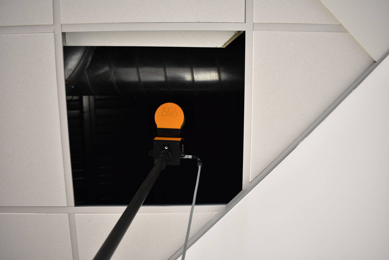 Mobile LiDAR scanner on a pole being elevated behind a ceiling void