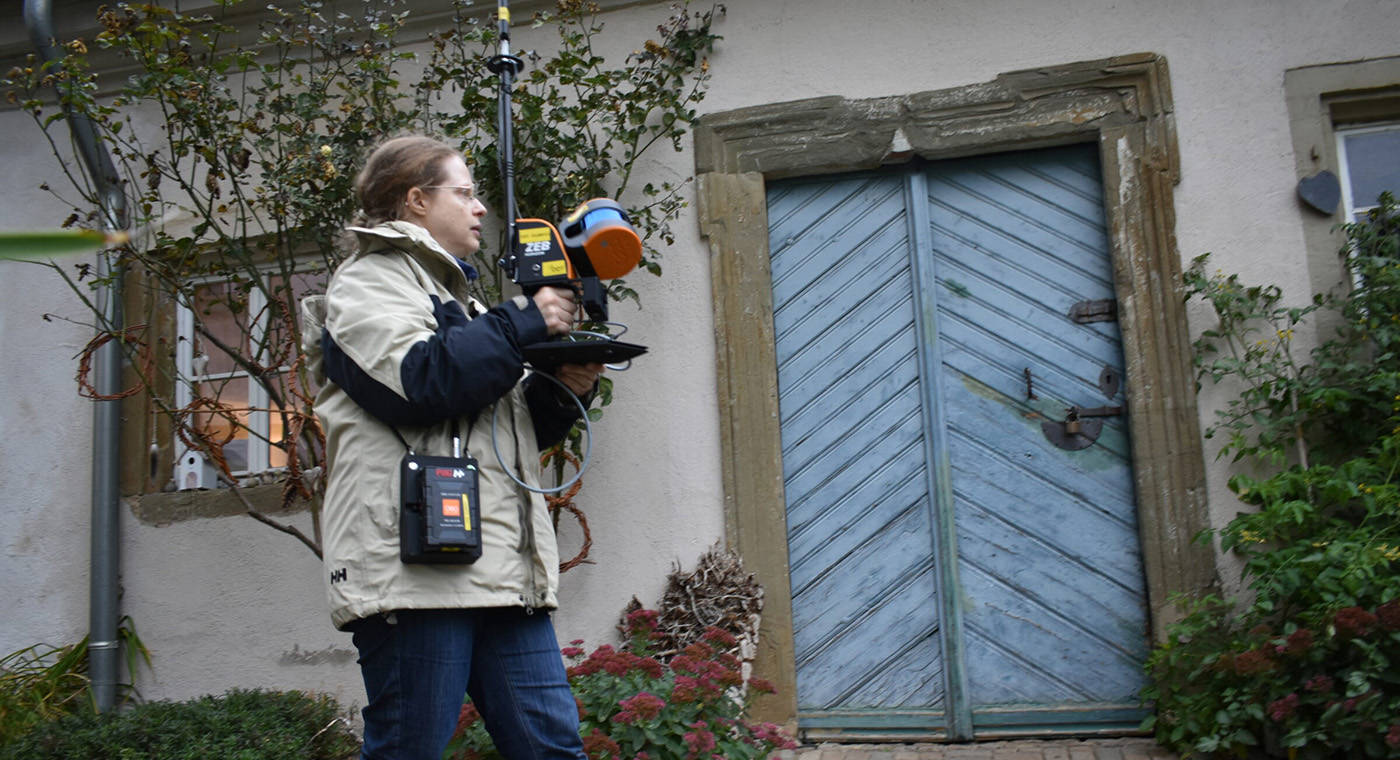 A lady in front of an old building entrance scanning with a mobile LiDAR solution