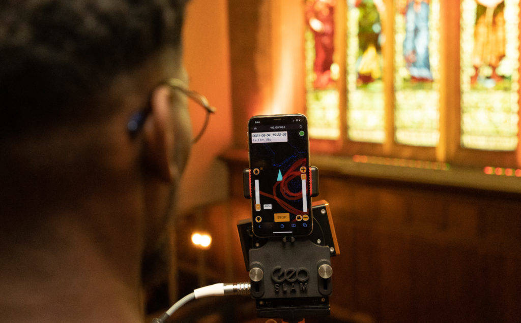 Person holding a mobile lidar scanner mapping a church