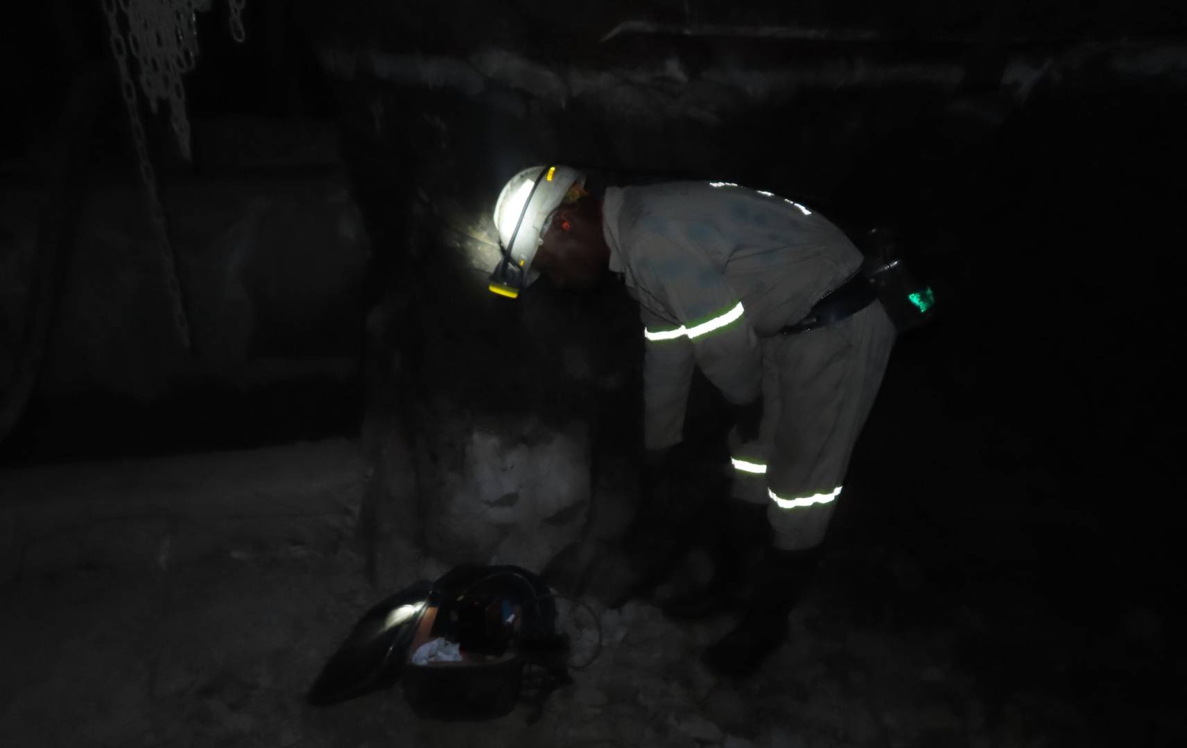 man in mine with hi-vis jacket bending over retrieving a mobile LiDAR scanner from a backpack