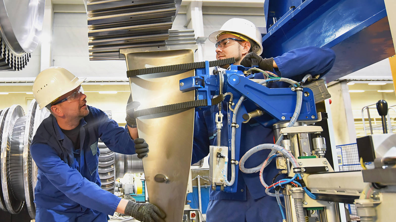 Two workers holding a component and using special equipment for large-scale parts assembly management