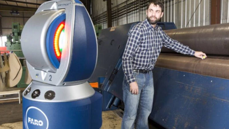 A worker using a FARO solution to check factory equipment alignment