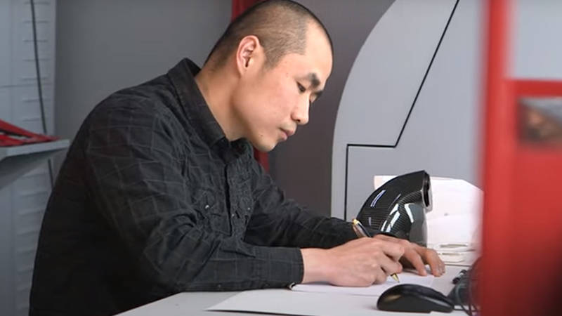 An automotive engineering professional at a desk, sketching a new Ferrari engine bay design