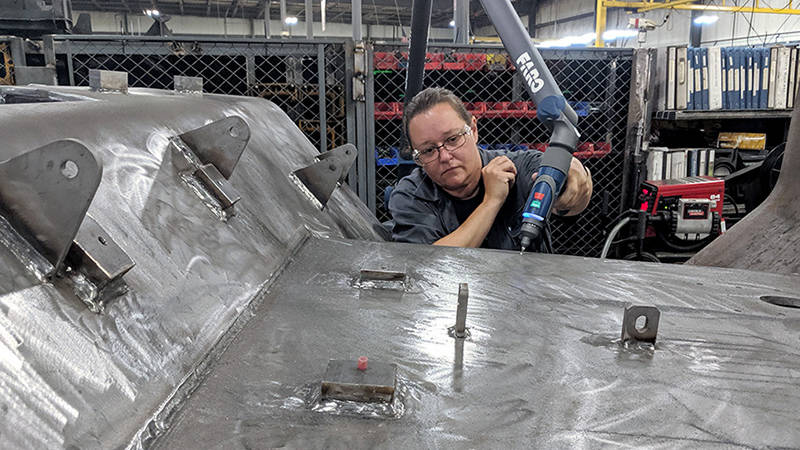 A worker at the Plasan military equipment manufacturing facility using a FARO ScanArm to check a large part