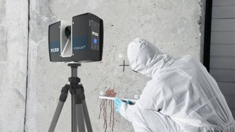 A forensic tech expert in safety gear studying a stain on a wall for 3D scanning