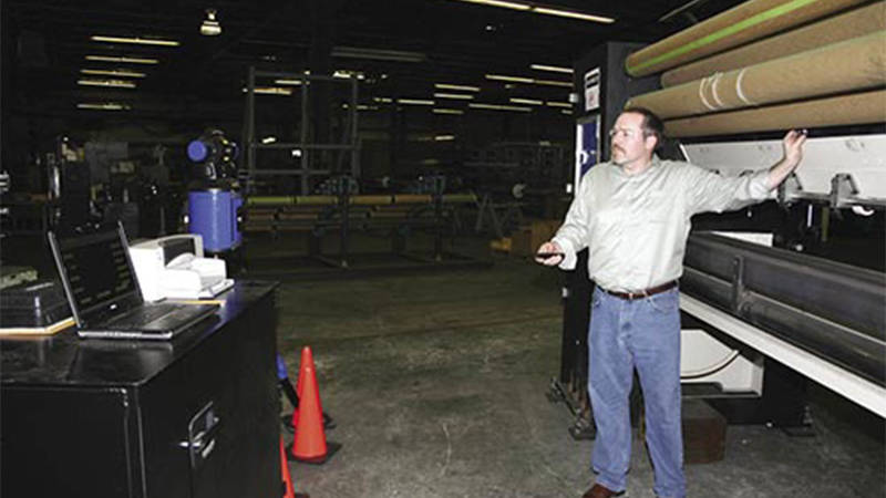 A worker at Tuftco Corporation adjusting a large carpet tufting machine