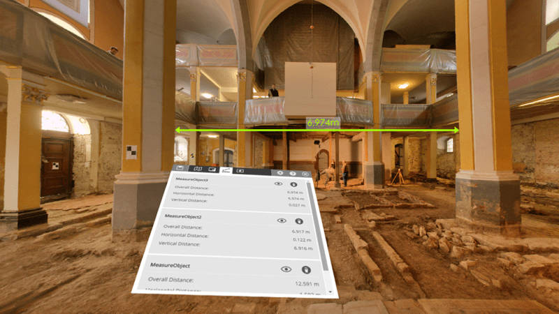 A virtual-reality view of a large room showing measured distance between two columns