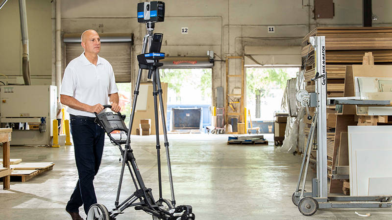 A worker moving a 3D laser scanner across a warehouse