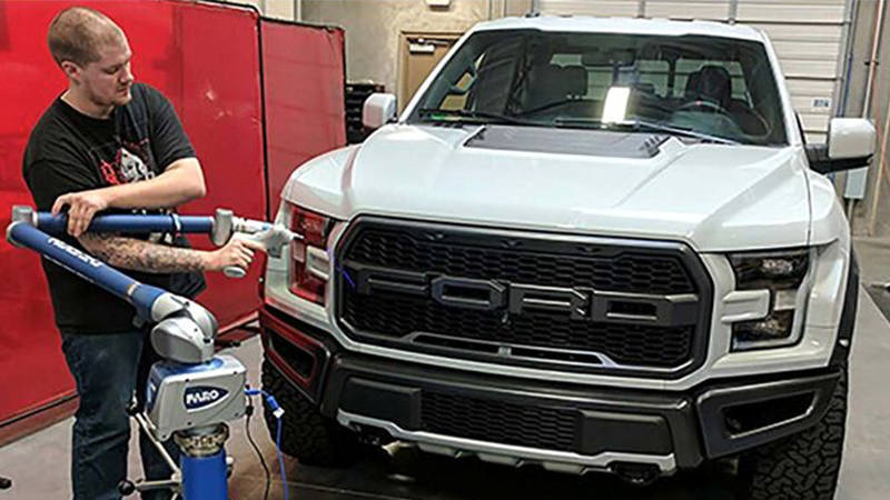 A worker uses a FARO 3D laser scanner to capture measurements of a vehicle part for aftermarket production