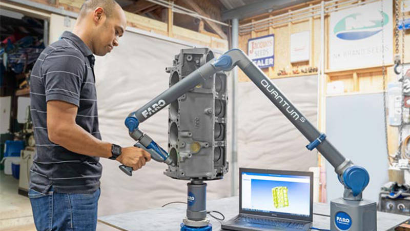 A worker using a FARO device and reverse engineering software to capture precision measurements of a part