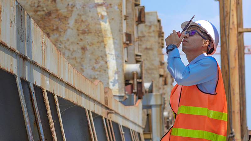 A director of quality speaking into a walkie-talkie during quality control inspection