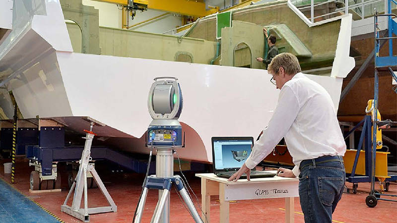 A worker reviewing a 3D scan of a manufactured yacht component for quality control